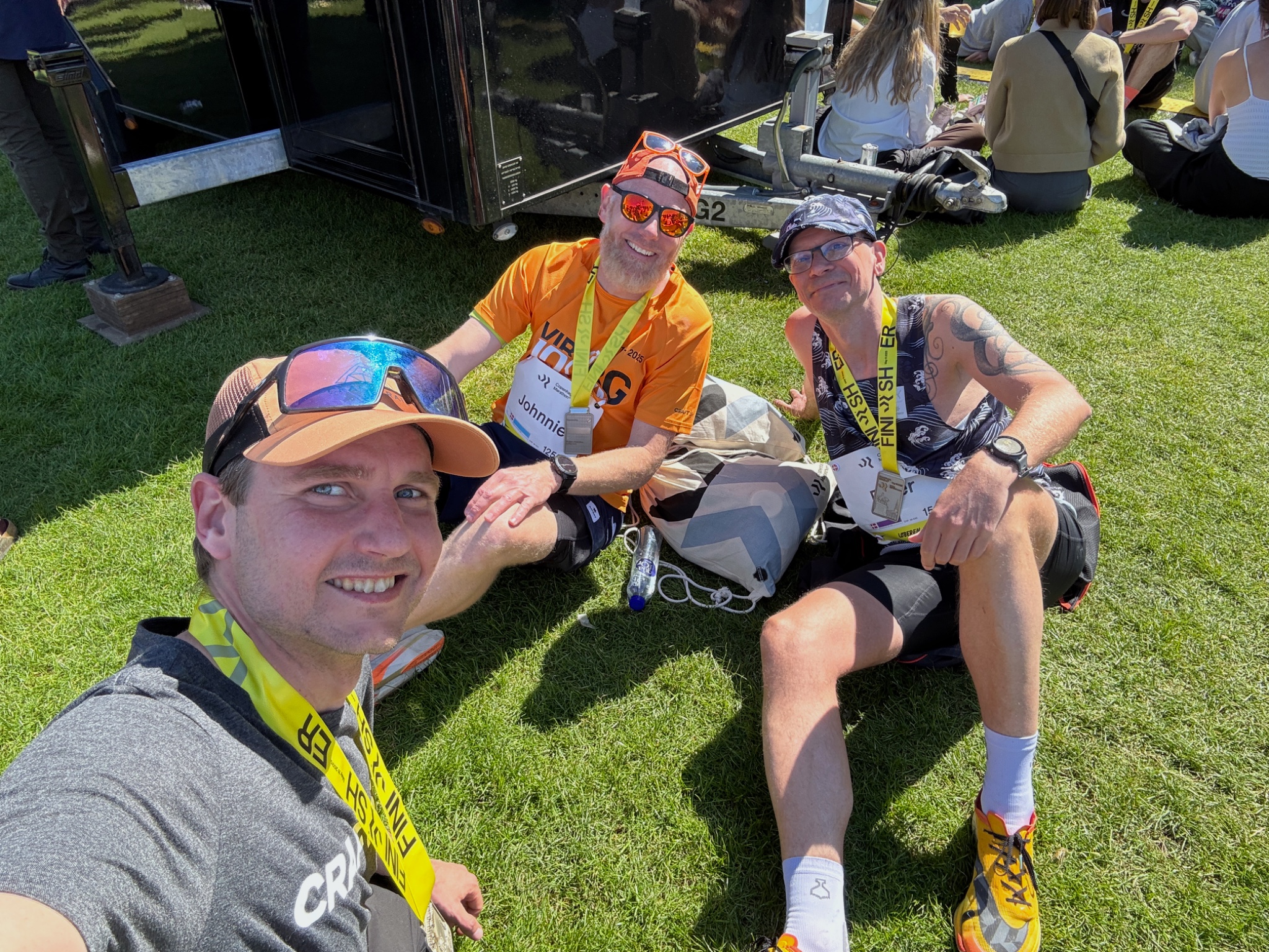 Three runners smiling together with medals after a race